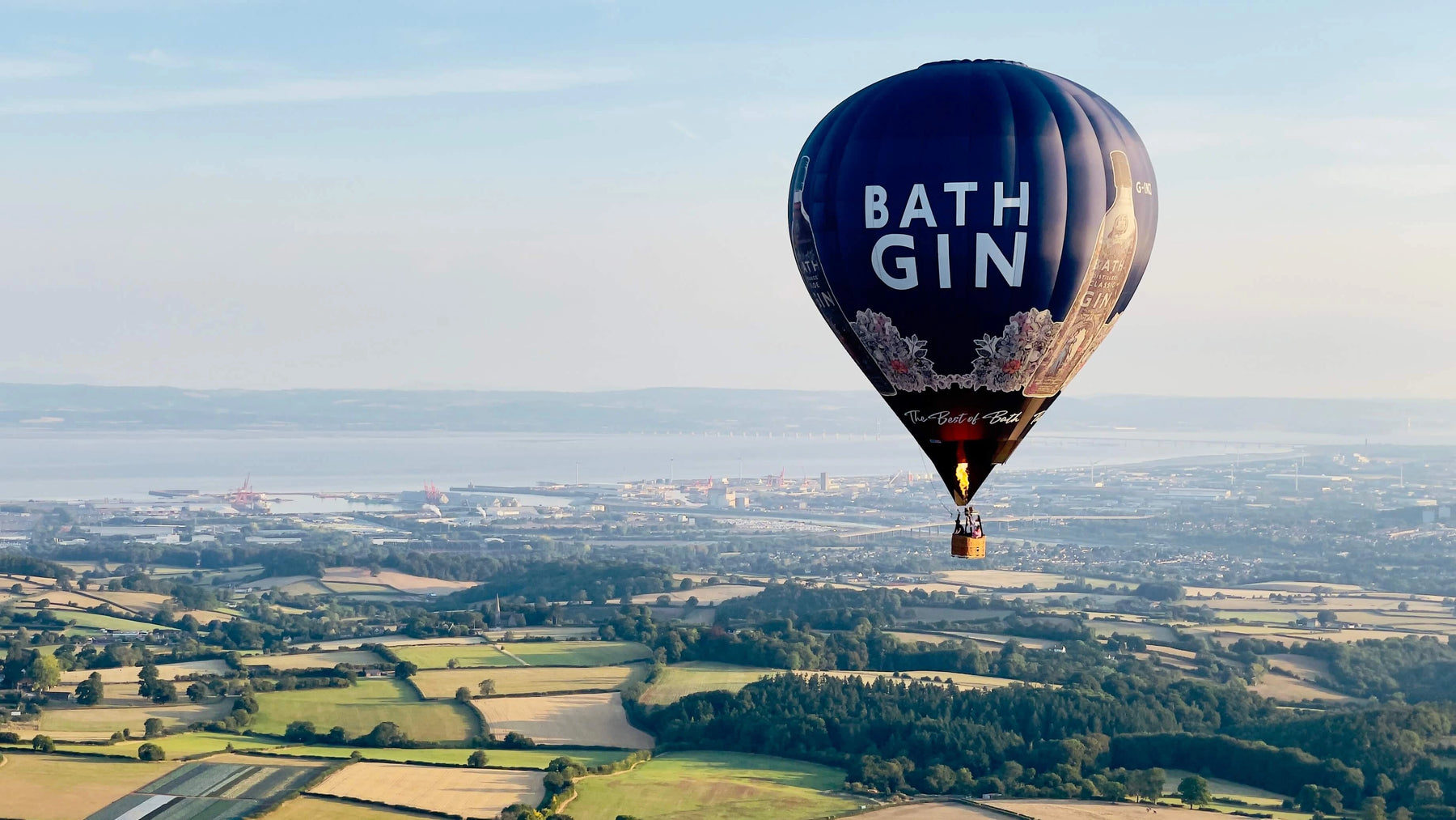 Bath Gin hot air balloon flying above Somerset countryside near Wells with distant views across the landscape