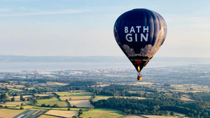 Bath Gin hot air balloon flying above Somerset countryside near Wells with distant views across the landscape