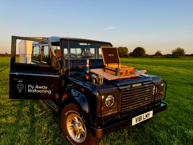 Post-flight champagne celebration set up on a Land Rover Defender in a scenic countryside field, part of the Fly Away Ballooning Experience