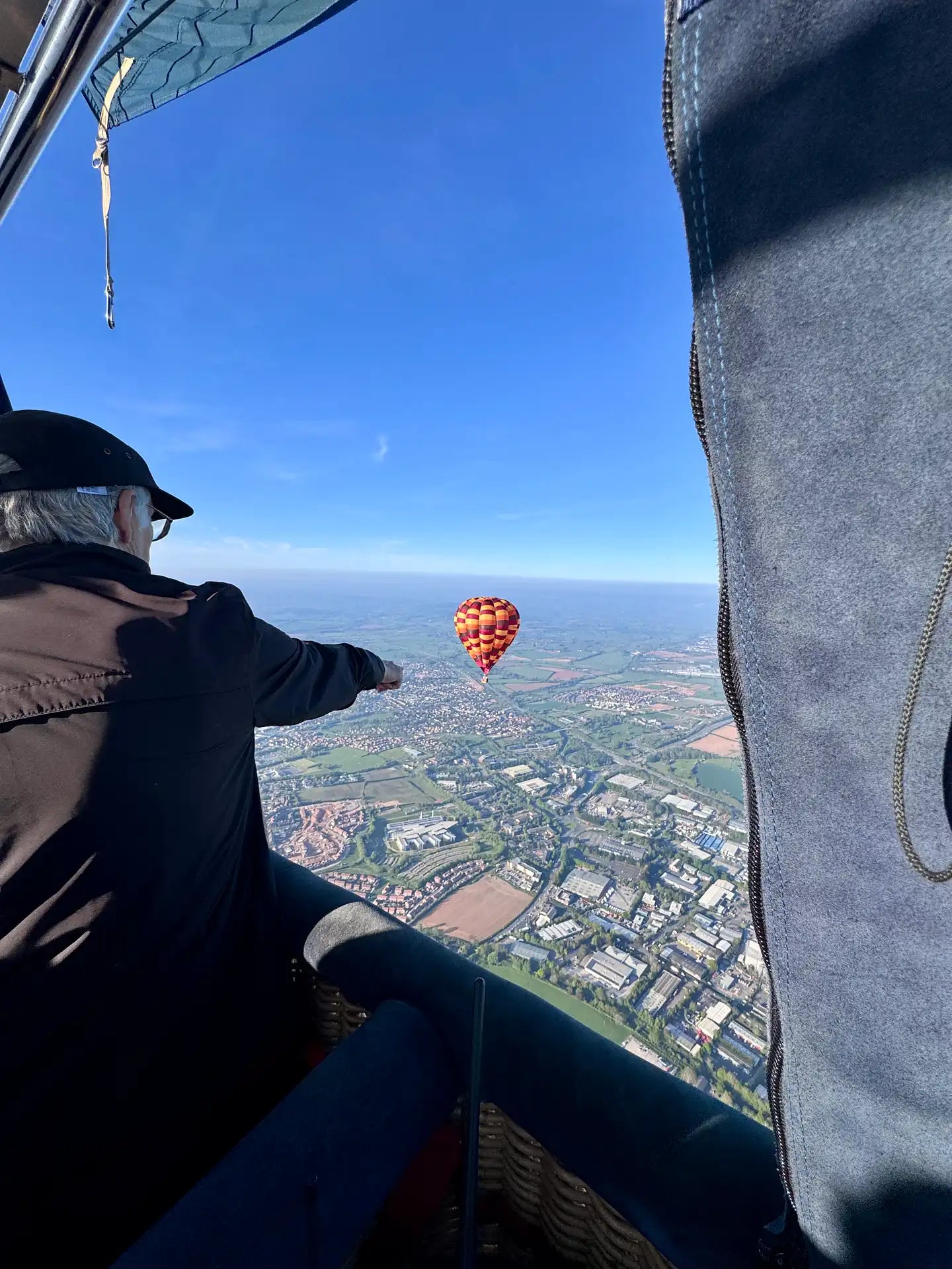 Passenger pointing to another hot air balloon flying above Exeter and the Devon countryside