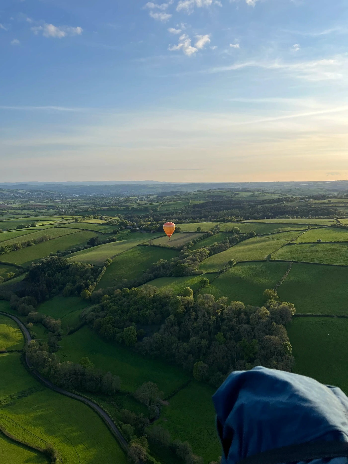 Hot air balloon flying over rolling countryside near Tiverton in Devon at sunset