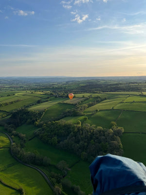 Hot air balloon flying over rolling countryside near Tiverton in Devon at sunset