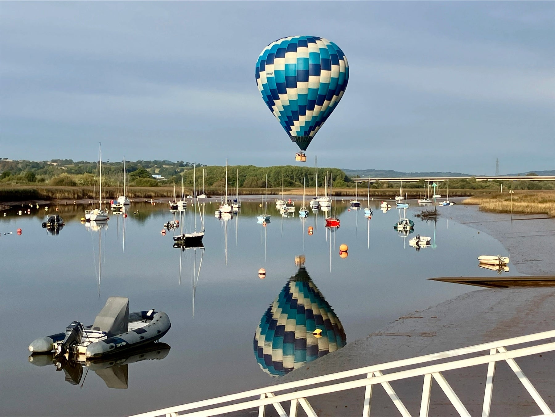 Hot air balloon flying over Topsham on the River Exe in Devon with boats and reflections at sunrise