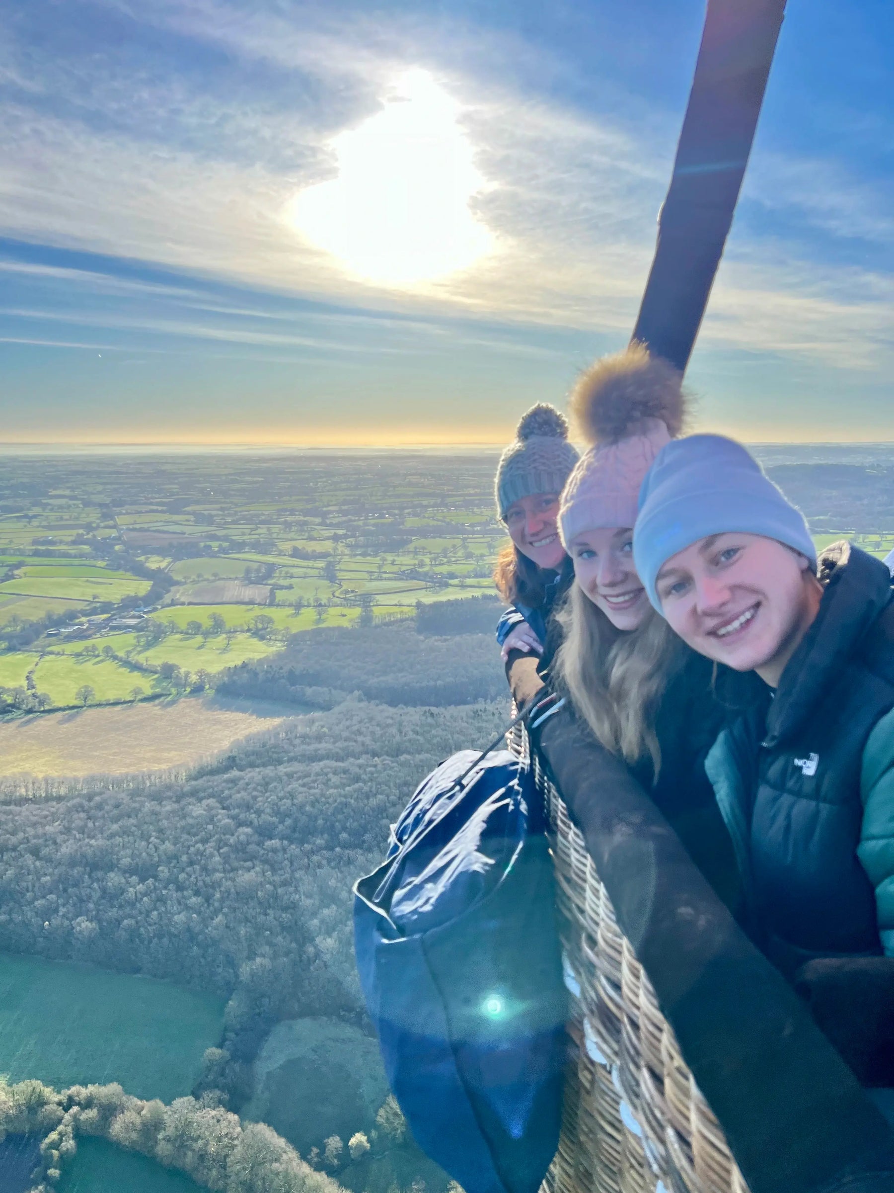 Passengers smiling in a hot air balloon basket during a flight over Somerset countryside near Taunton