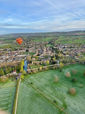 Hot air balloon flying over Wells Cathedral and the Bishop’s Palace in Somerset, England, with countryside views, captured during a Fly Away Ballooning flight.